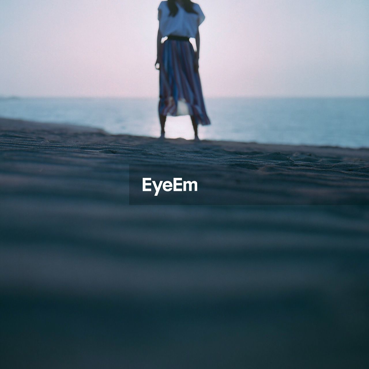 Low section of woman standing at beach