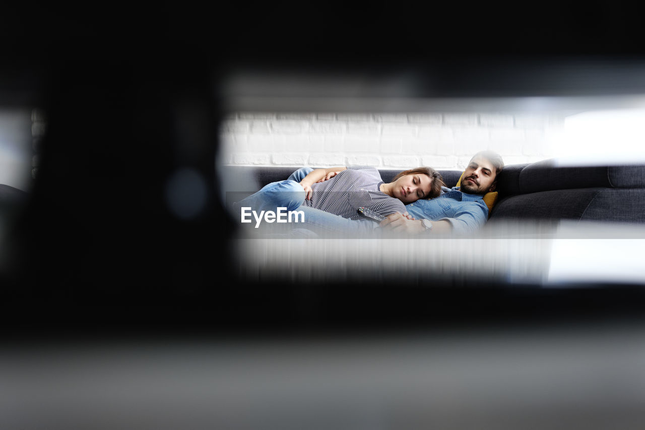 Couple relaxing on sofa while watching tv at home