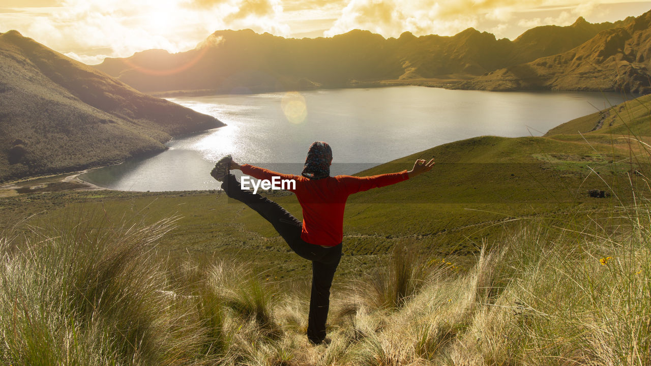 Concentrated young latina woman practicing yoga alone in front of the mojanda lagoon