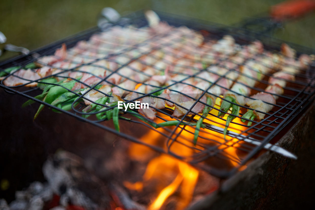 Grilled fresh onion covered by bacon in open fire. selective soft focus.