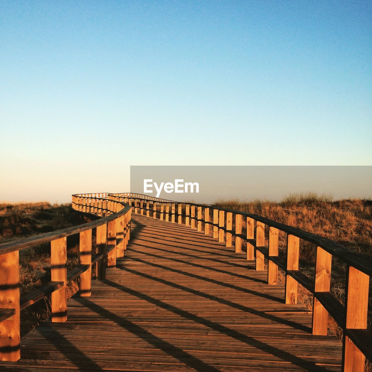 Footbridge over field against clear sky