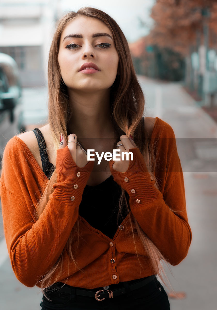 Portrait of beautiful young woman standing on footpath