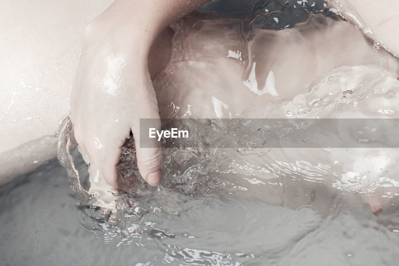 Midsection of naked woman in water
