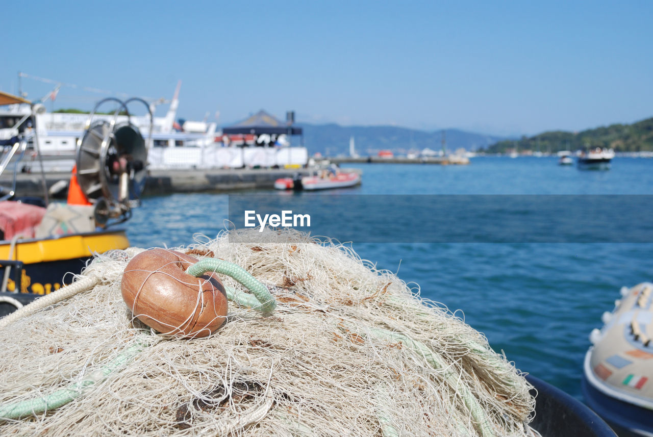 Fishing boats moored at harbor against clear sky