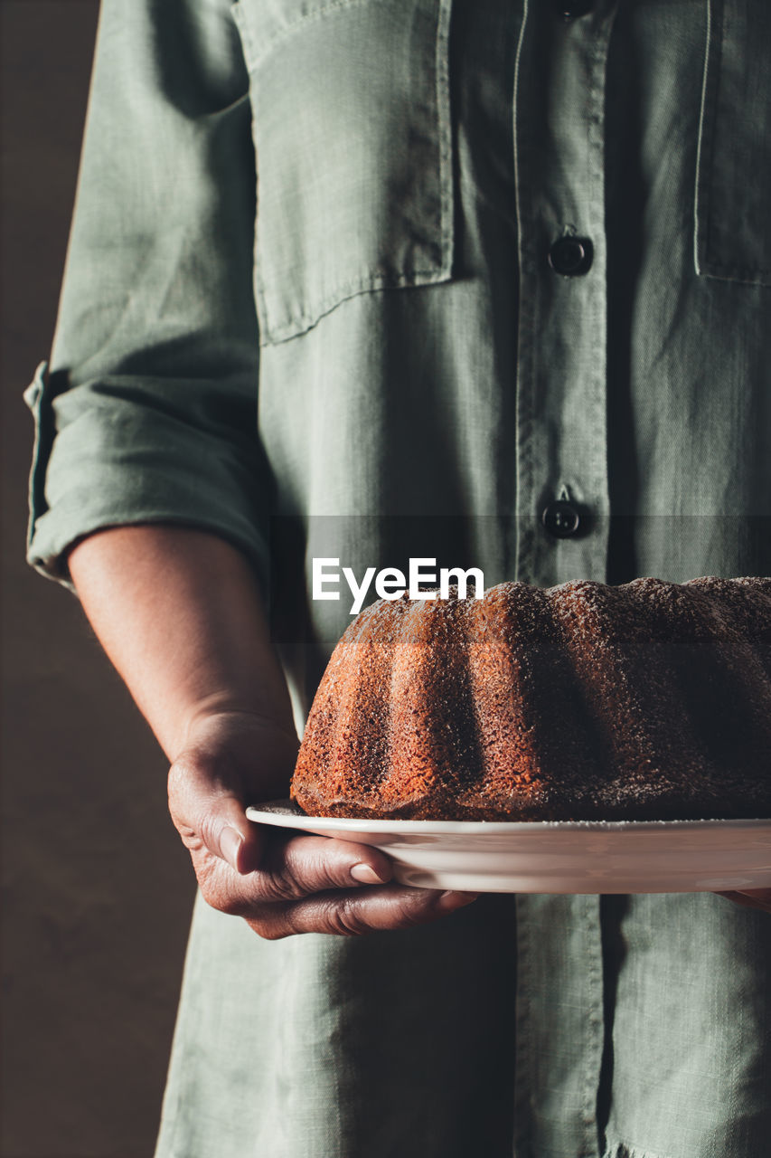 Midsection of man holding bundt cake in plate