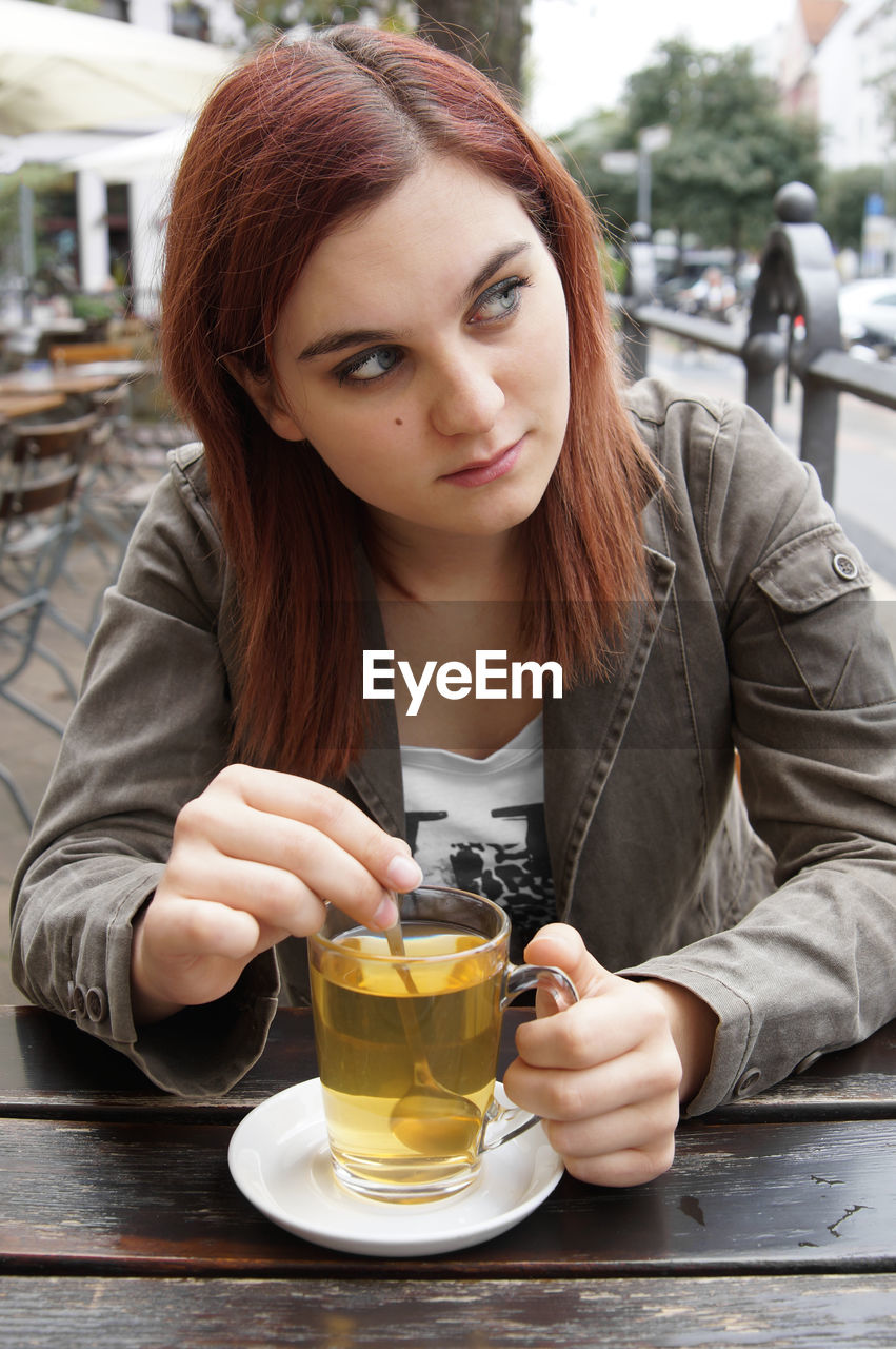 Thoughtful woman having tea at sidewalk cafe