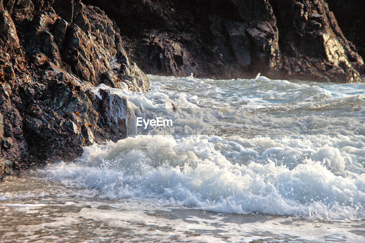 SCENIC VIEW OF WAVES BREAKING ON ROCKS