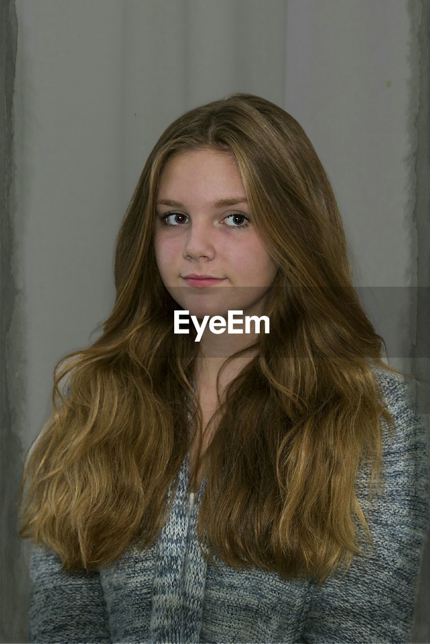 Close-up of beautiful young woman against wall