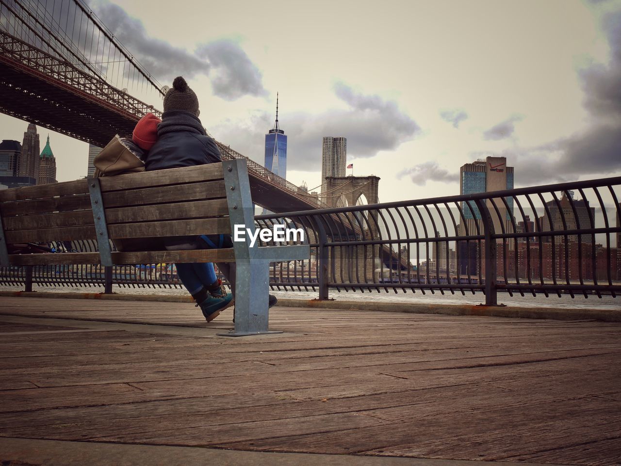 Rear view of couple sitting on bench at promenade at manhattan