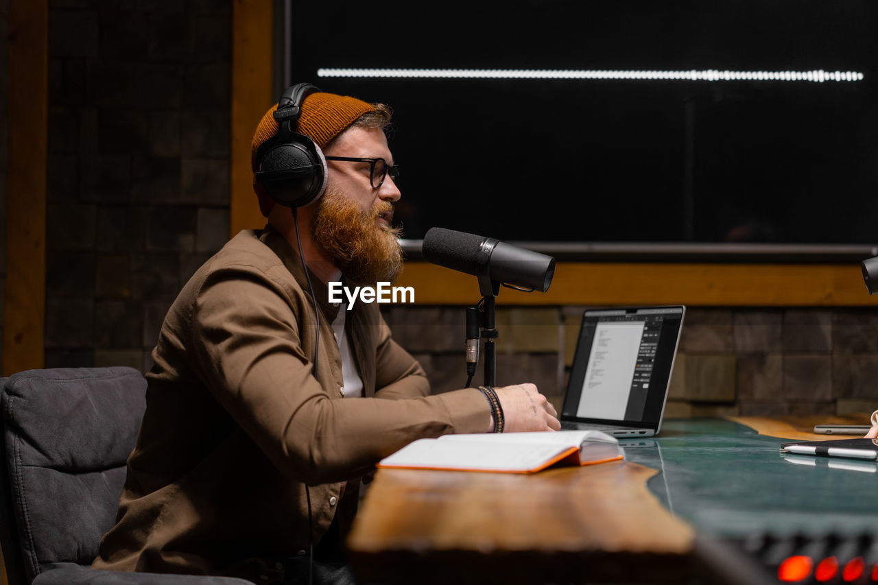 Male podcaster interviewing a guest in a recording studio