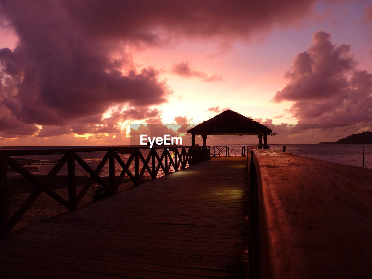 Pier over sea against sky during sunset