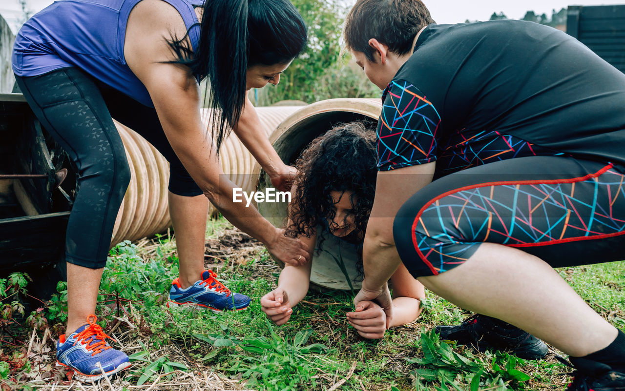 Women helping friend in coming out of pipe