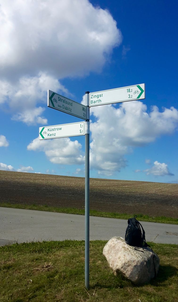 ROAD SIGN BY POLE AGAINST SKY