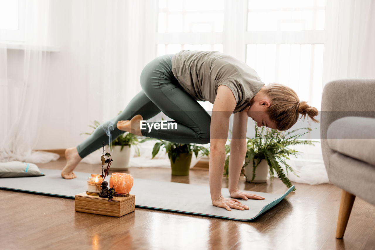 Beautiful young woman doing exercises and doing yoga at home