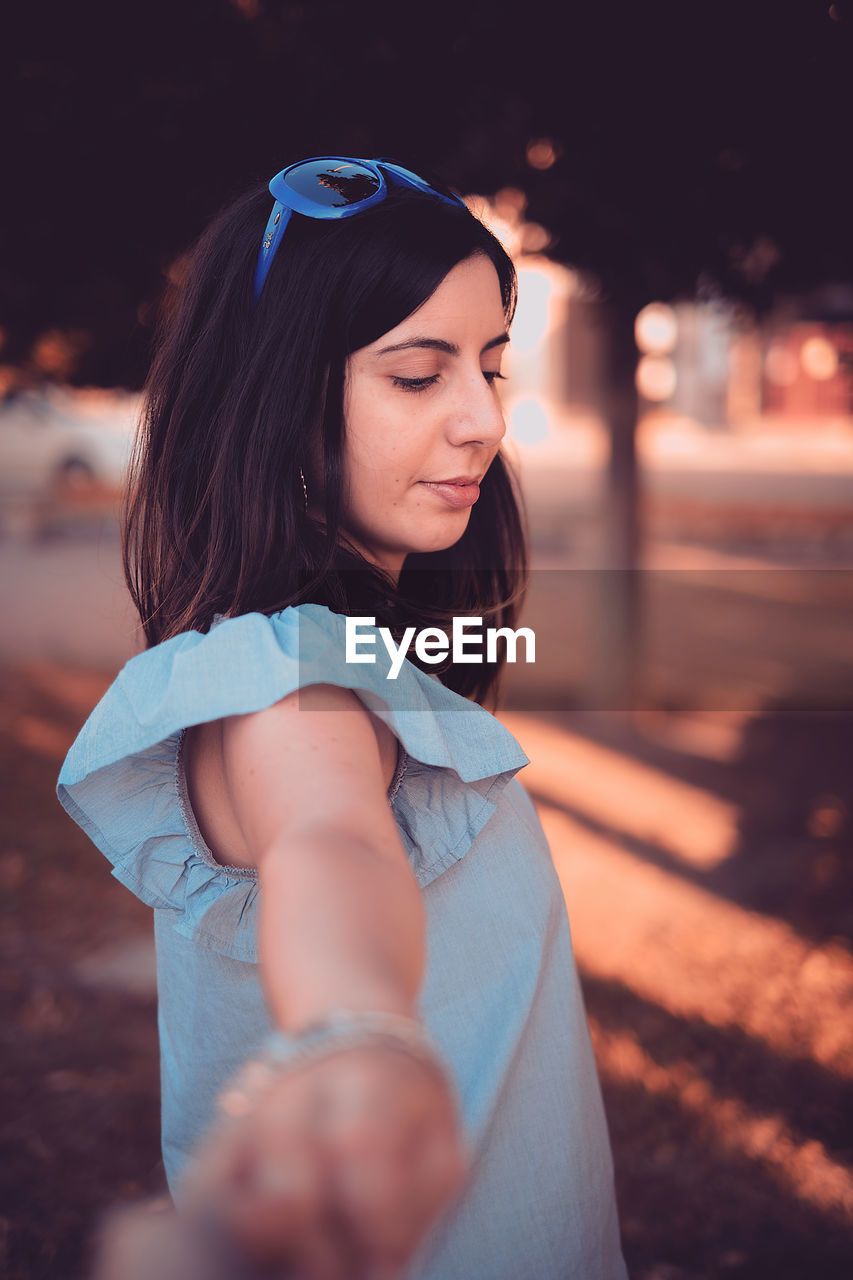 Close-up of man's hand holding hand of young woman standing on street during sunset