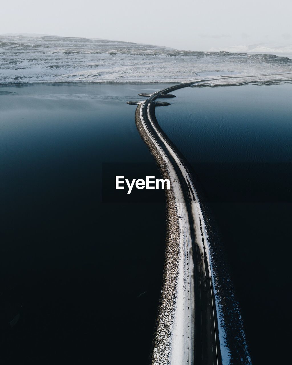 Road amidst sea during winter