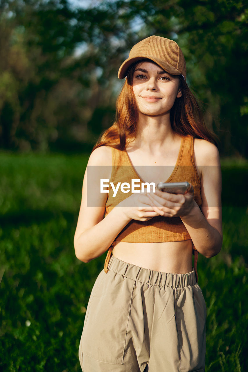 portrait of young woman wearing hat while standing on field