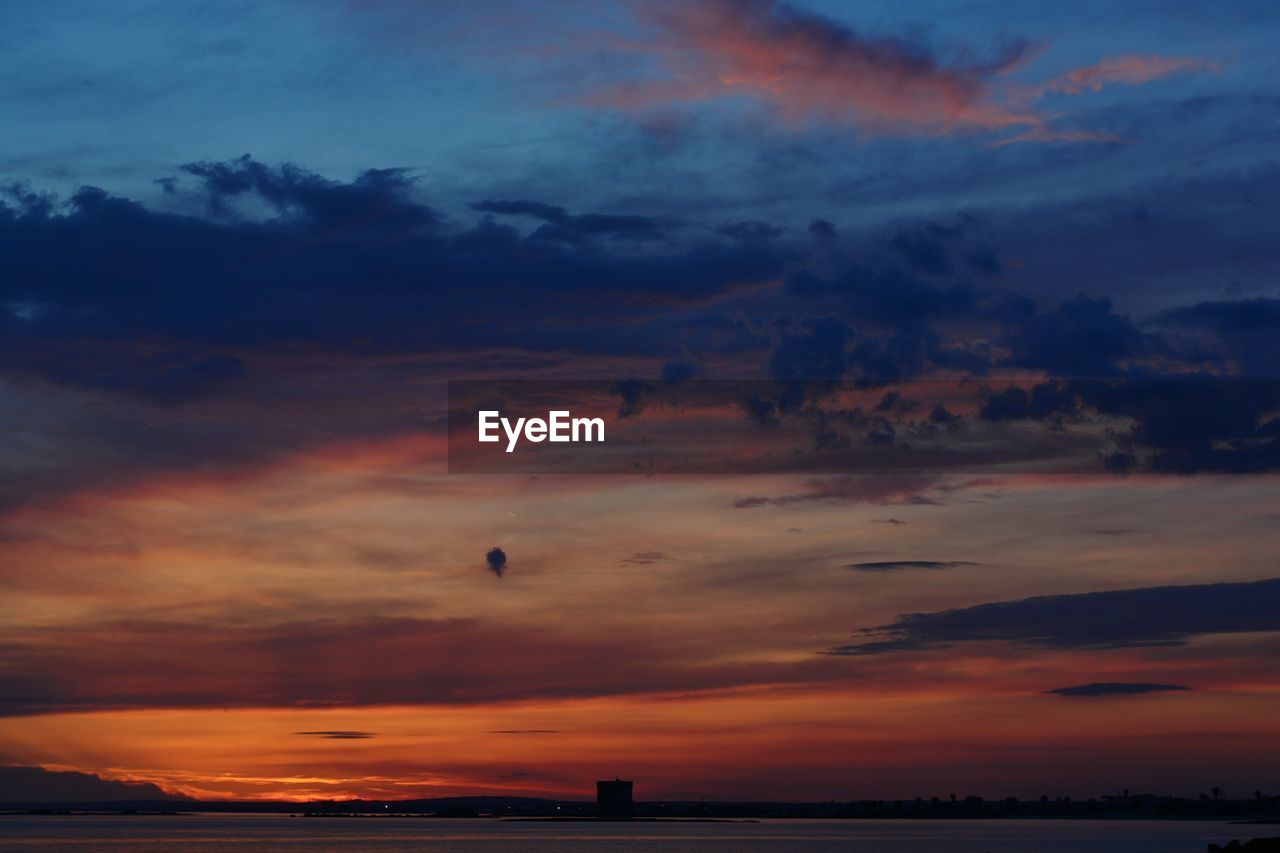 Scenic view of lake against cloudy sky during sunset