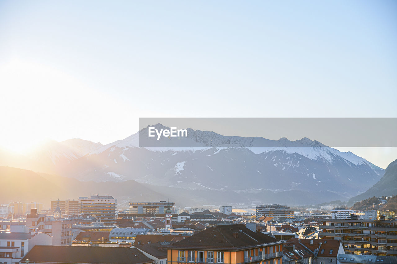 Townscape by mountains against clear sky during winter