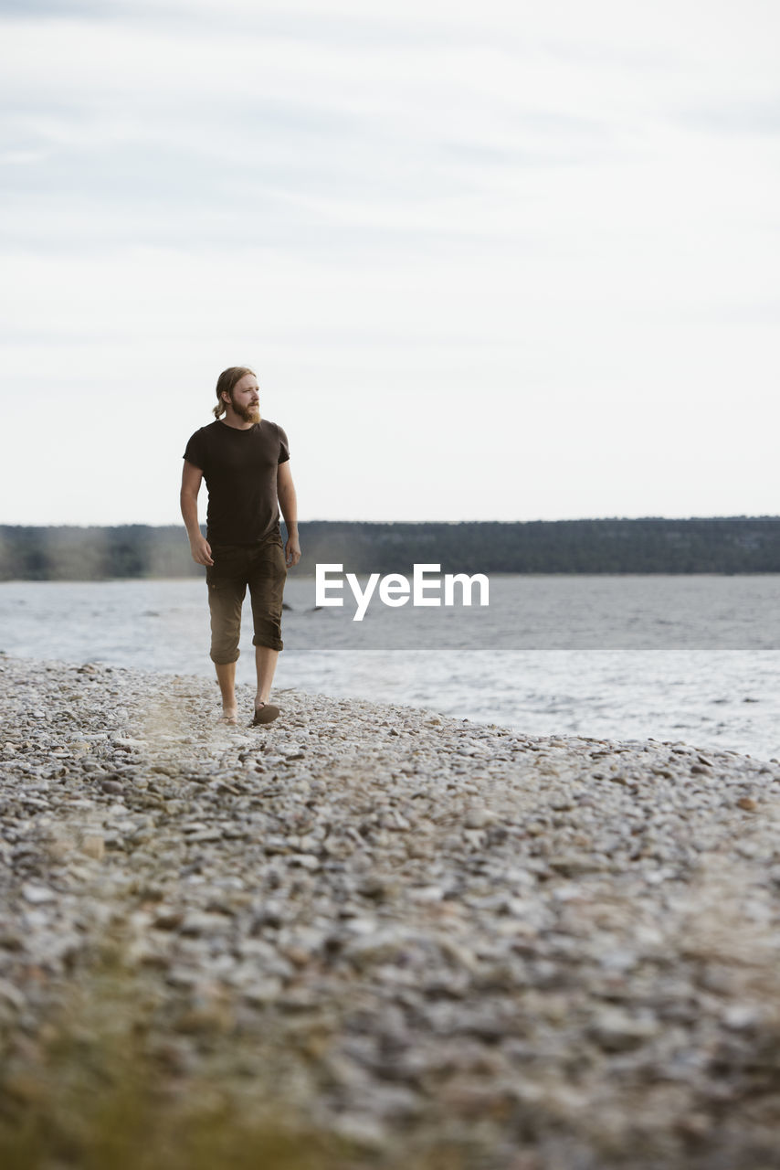 Young man walking on beach, gotland, sweden