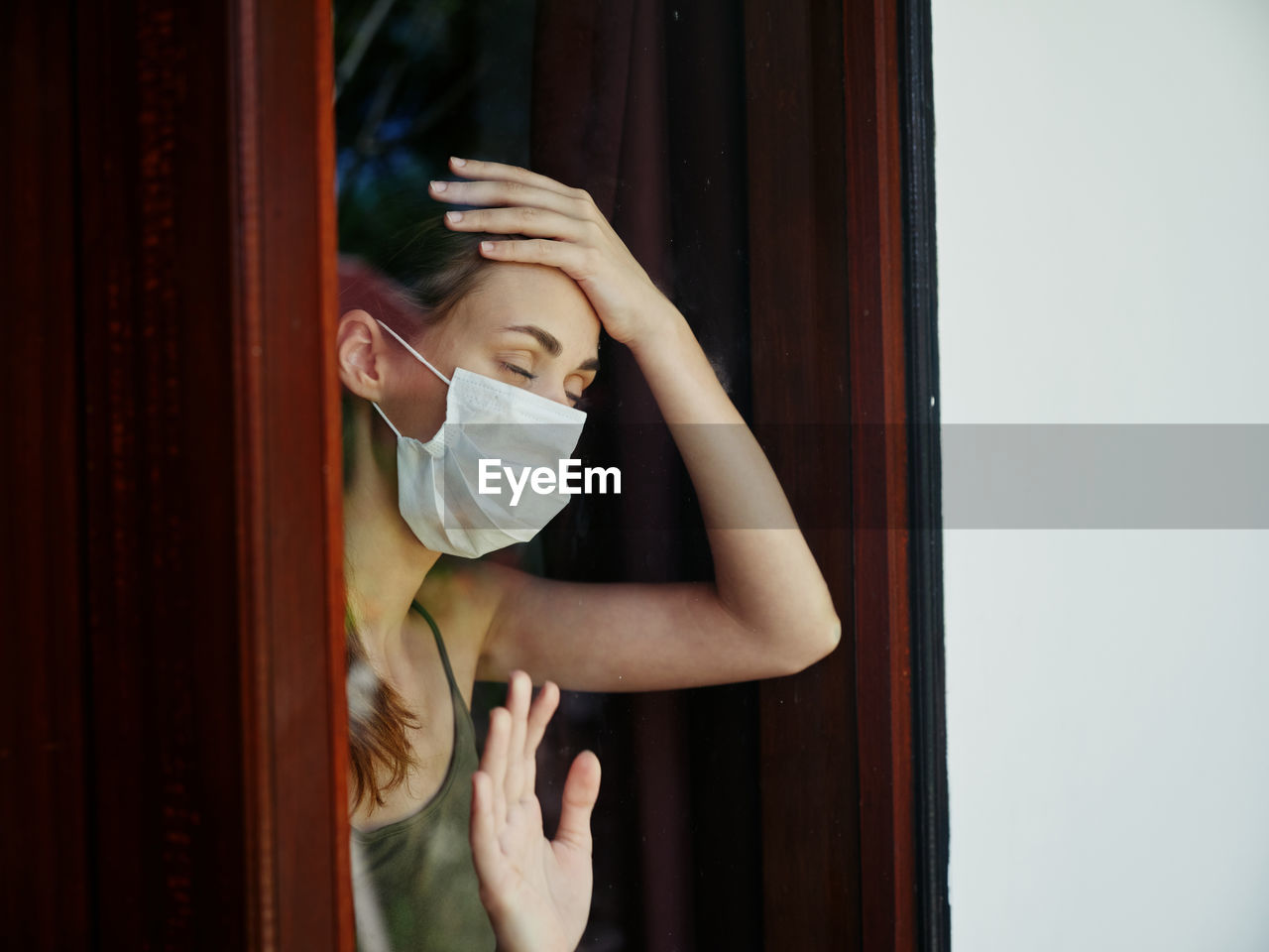 Midsection of woman standing by window at home