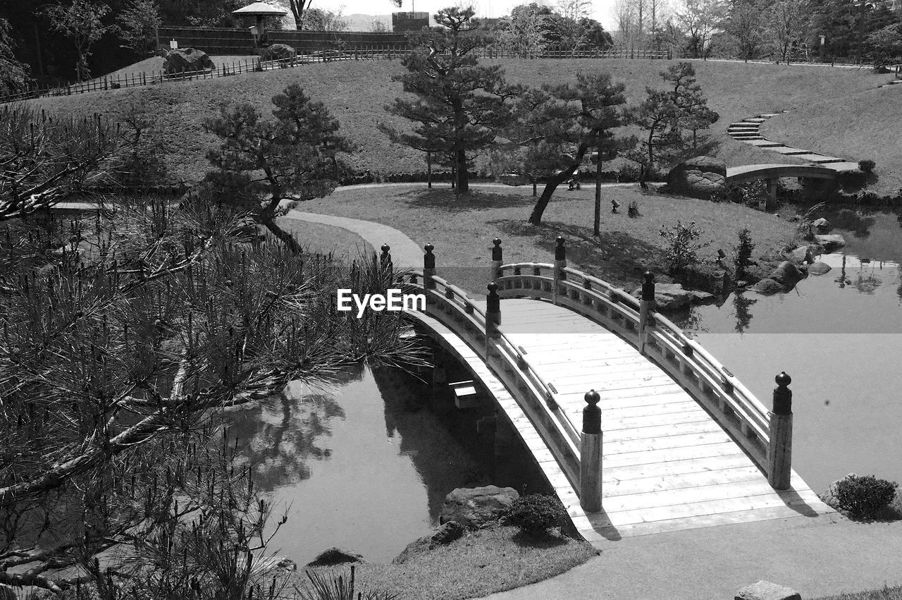 HIGH ANGLE VIEW OF BRIDGE OVER LAKE AGAINST TREES