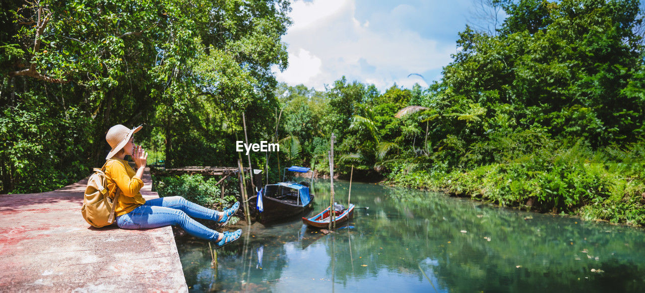 rear view of woman sitting in boat on lake