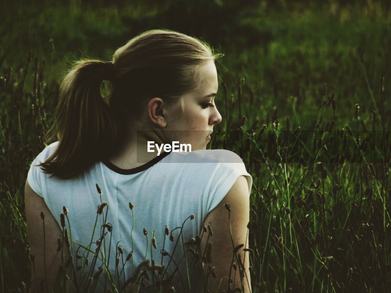 PORTRAIT OF YOUNG WOMAN STANDING ON GRASSY FIELD