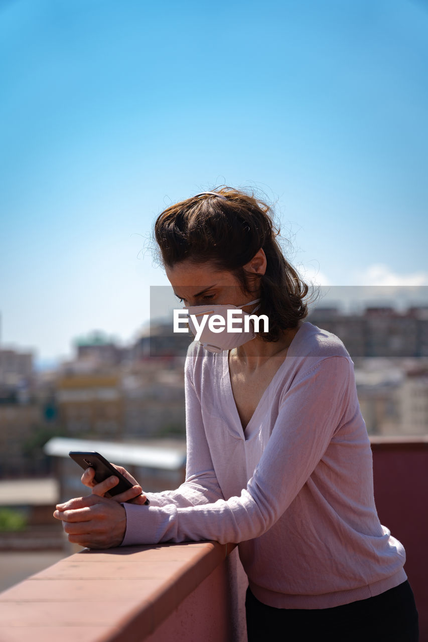 Woman using phone while standing at building terrace