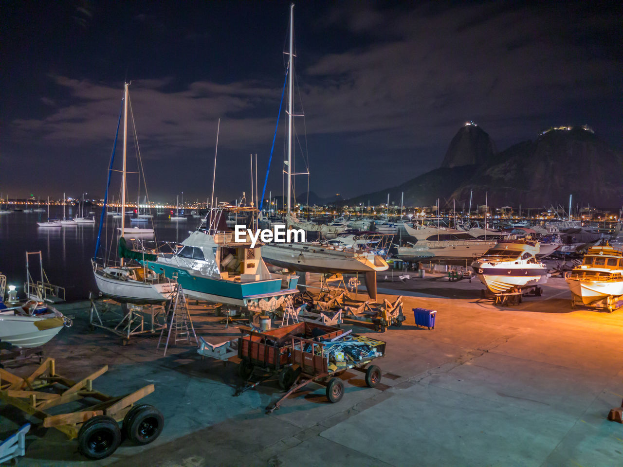 BOATS MOORED AT HARBOR DURING NIGHT