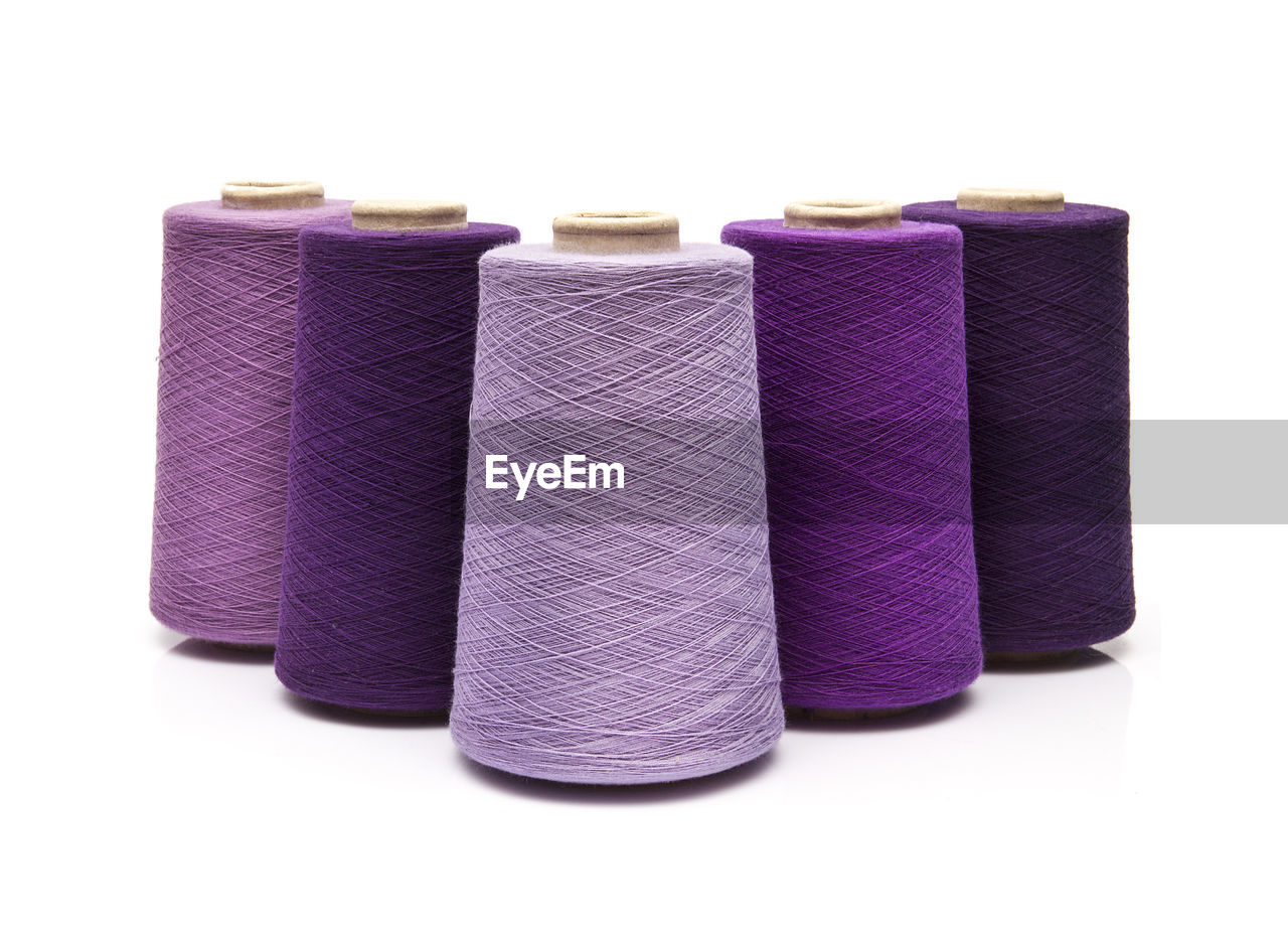 Close-up of purple thread spool over white background