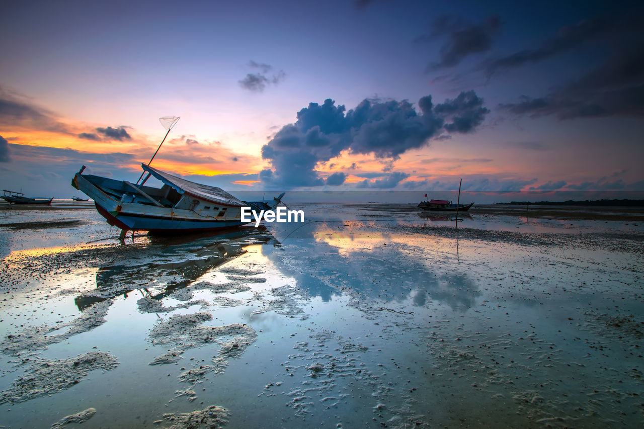 Boat moored in sea against sky during sunset