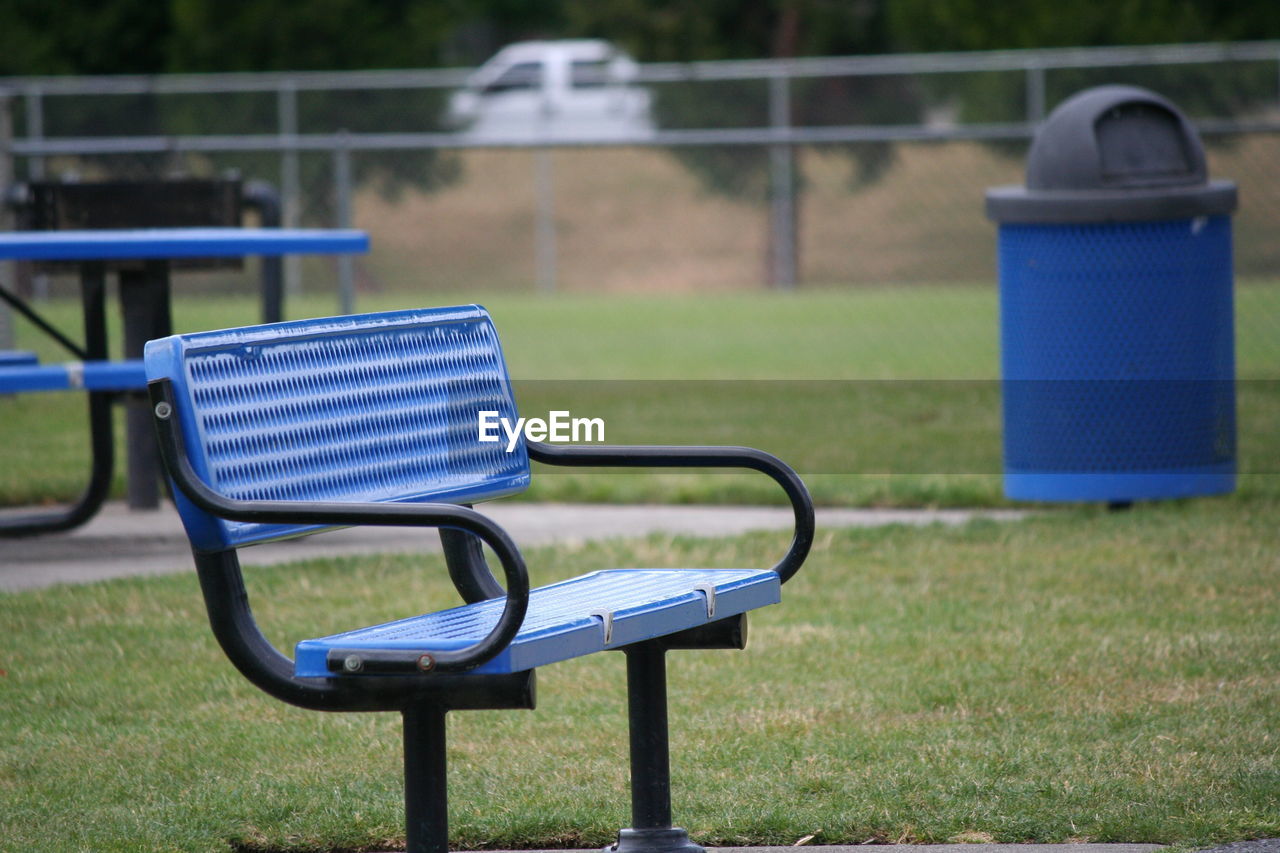 Empty blue bench on field in park