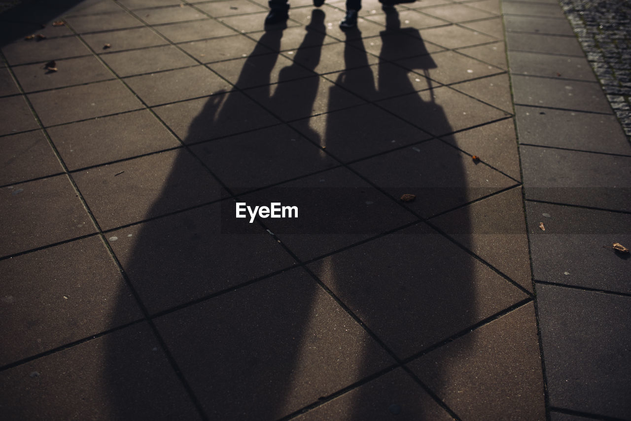 HIGH ANGLE VIEW OF PEOPLE WALKING ON TILED FLOOR