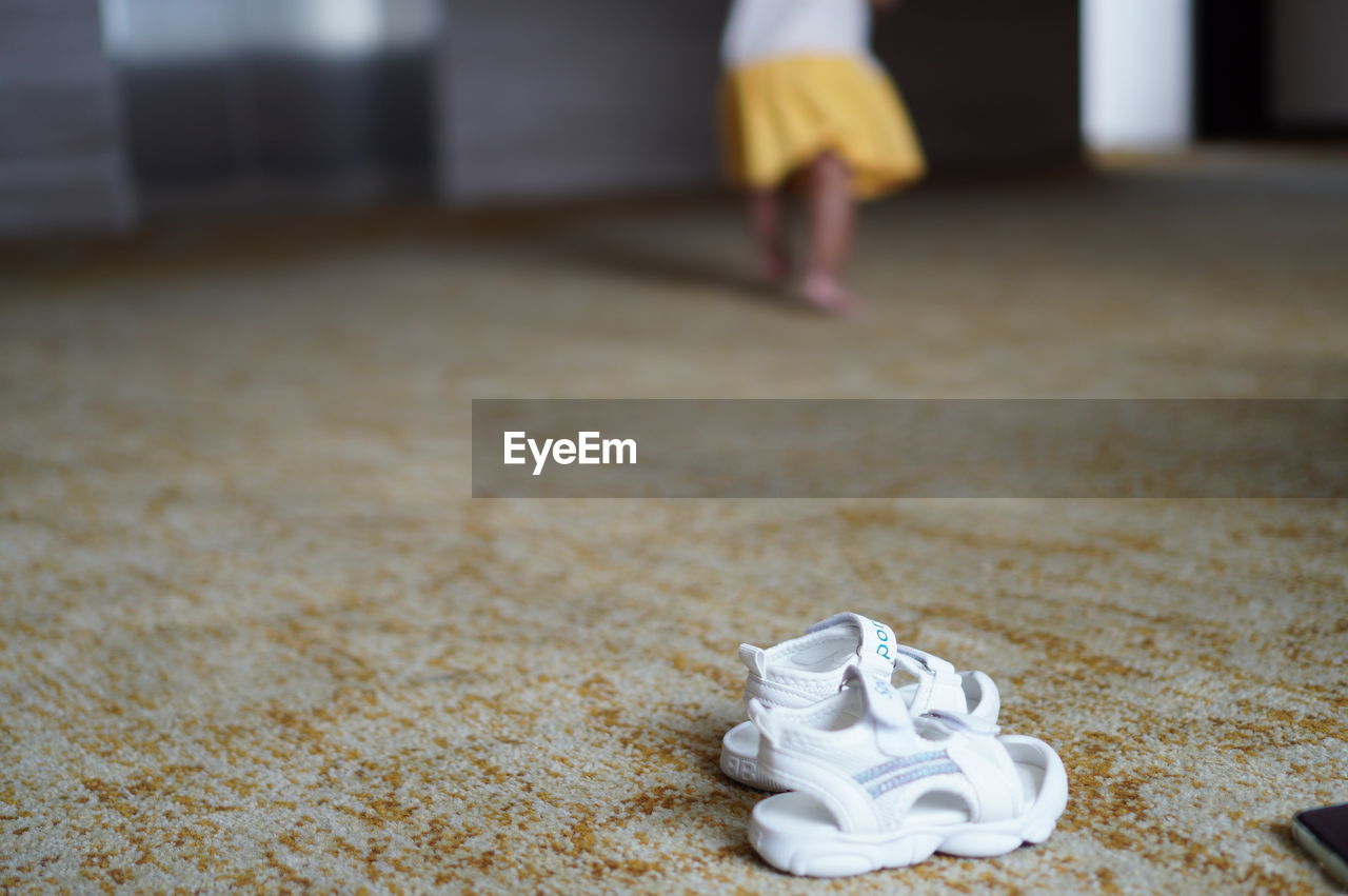 one person, flooring, white, indoors, carpet, low section, floor, shoe, yellow, focus on foreground, childhood, child, human leg, footwear, day, standing