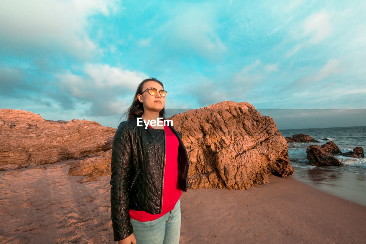 MAN STANDING ON ROCK AGAINST SEA