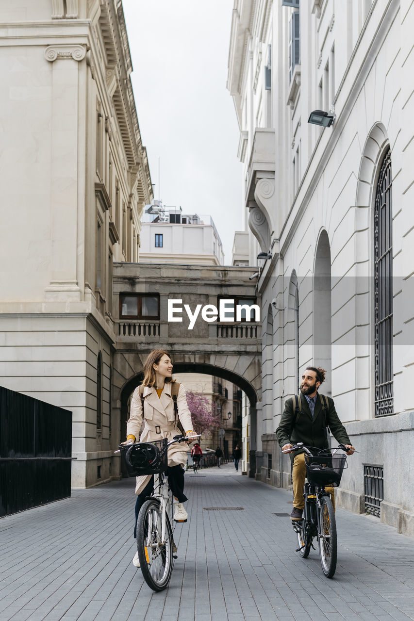 Smiling couple riding e-bikes in the city