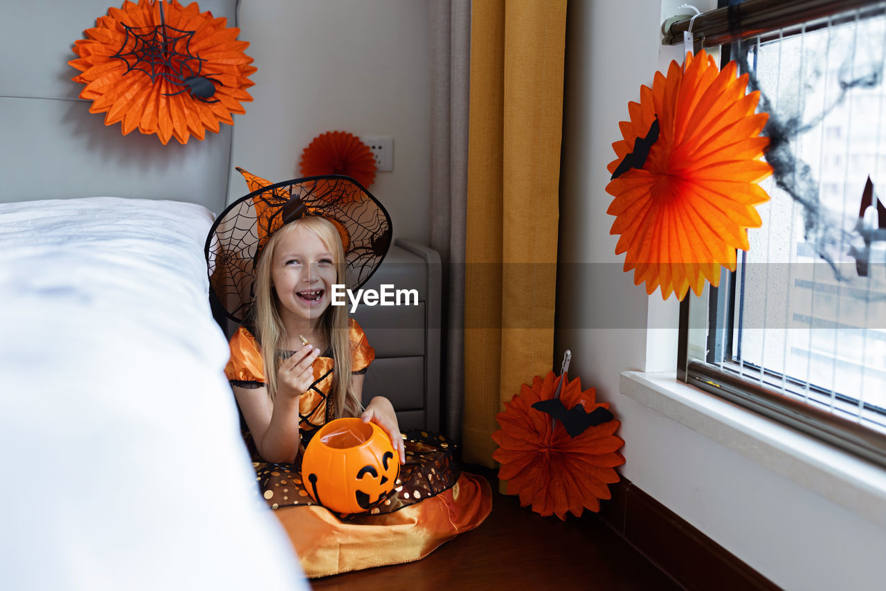 Portrait of smiling girl sitting at home during halloween