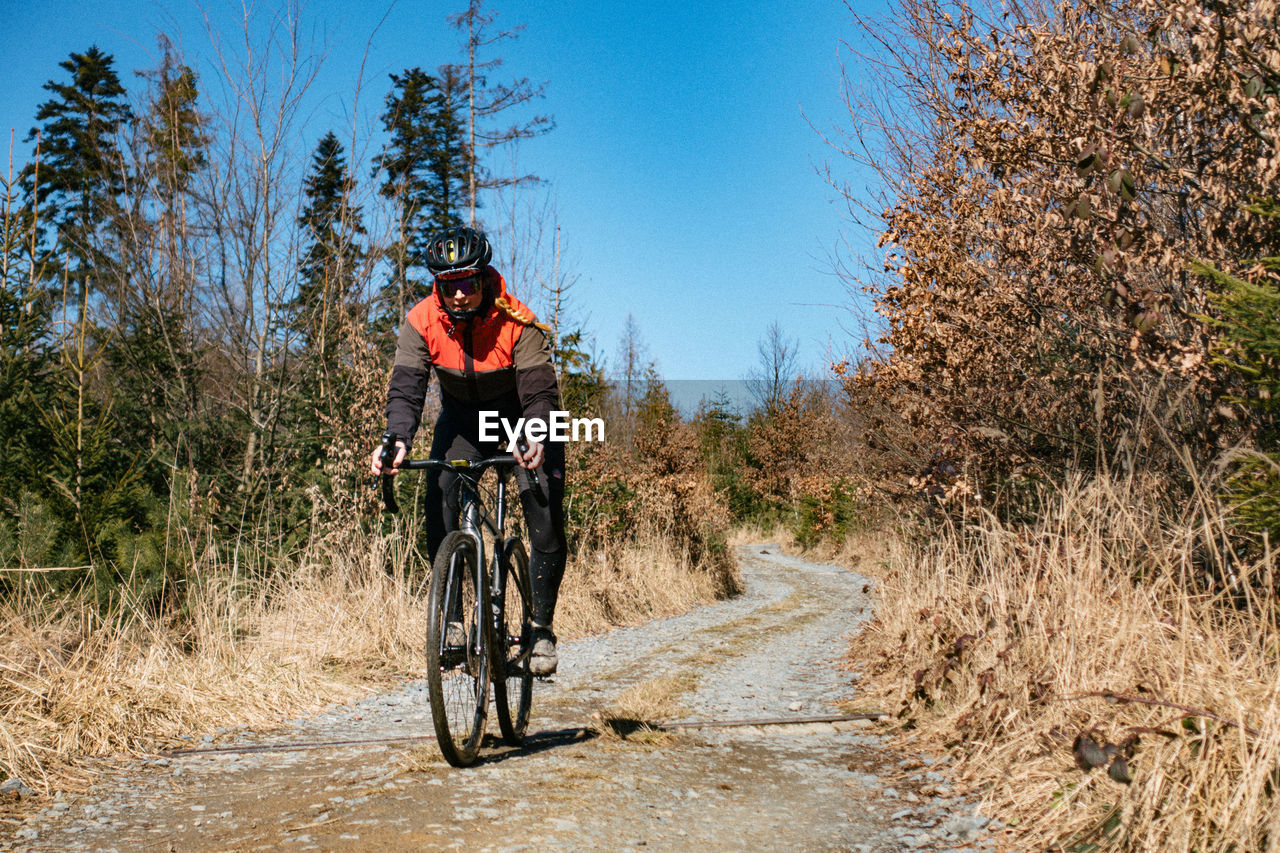 Woman riding bicycle on gravel road