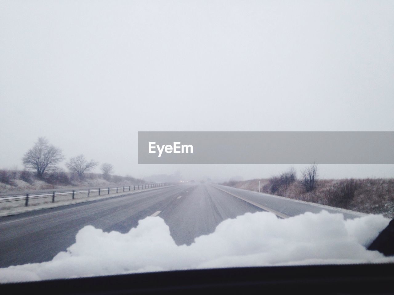 Snow on car windshield against clear sky during winter