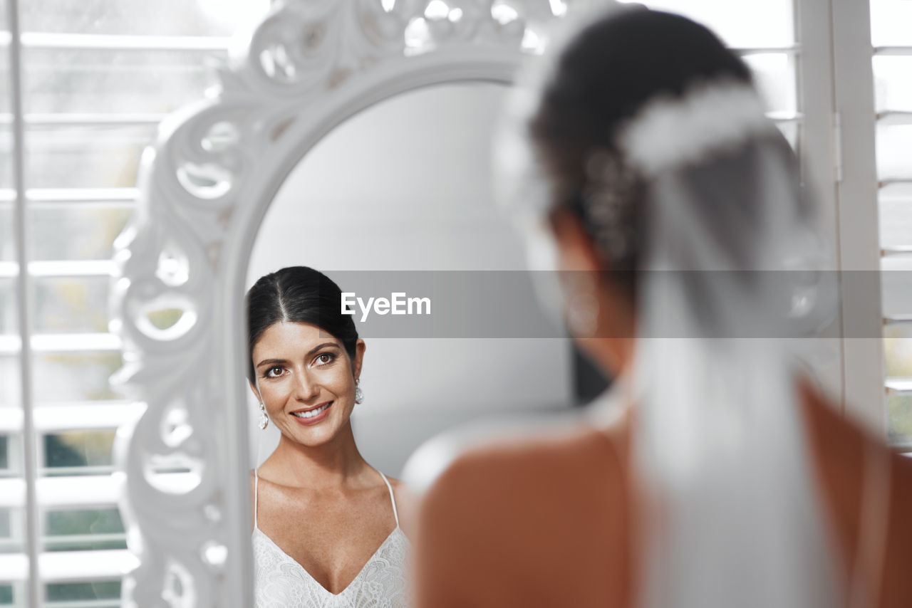 bride, wedding dress, women, adult, ceremony, indoors, wedding, two people, female, young adult, newlywed, smiling, portrait, happiness, human face, selective focus, headshot, emotion, dress, togetherness, mirror, fashion, celebration, business, event, person, clothing, looking, reflection, lifestyles, veil, bridal clothing, human hair, elegance, standing, bun