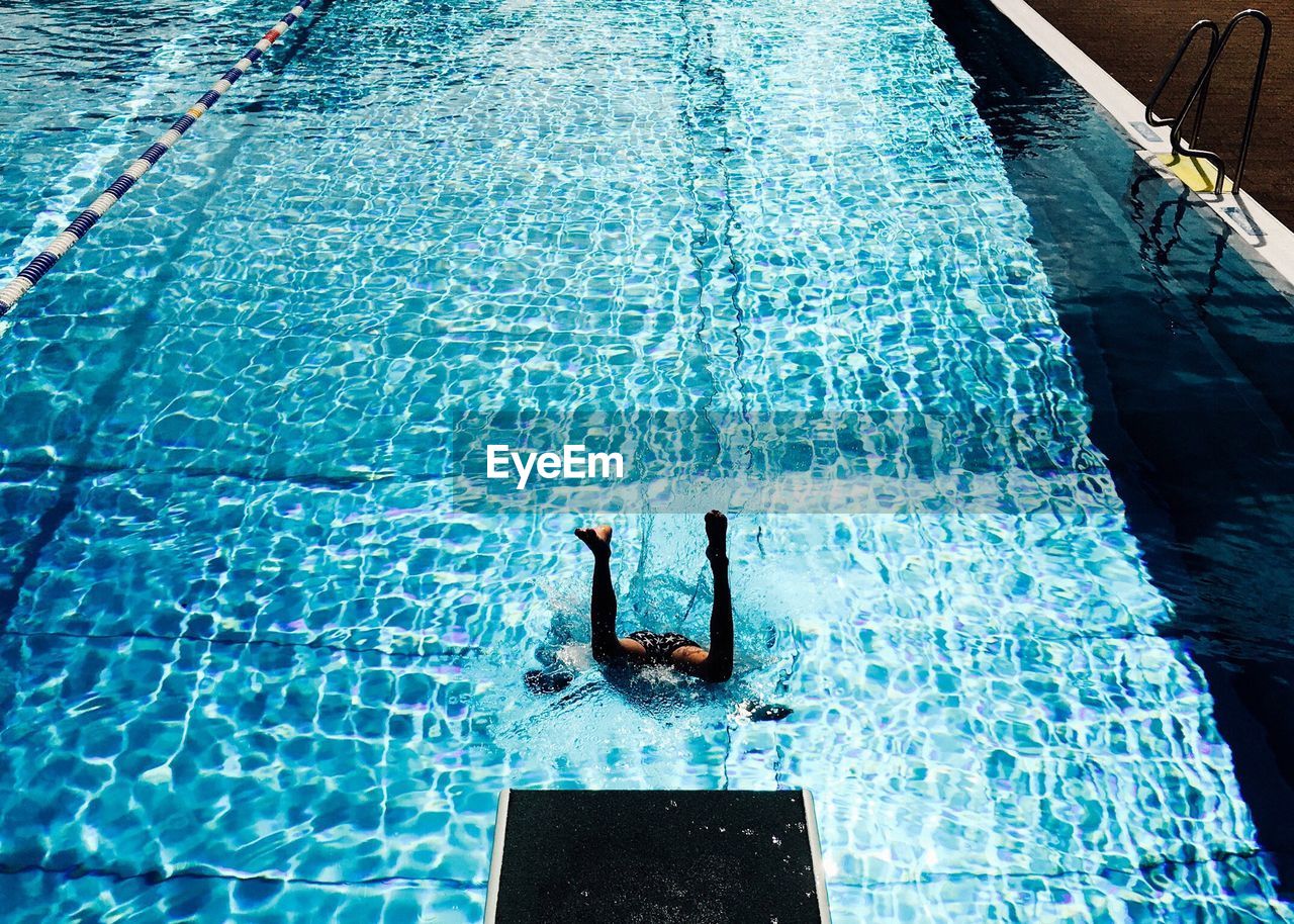 Low section of man jumping in swimming pool