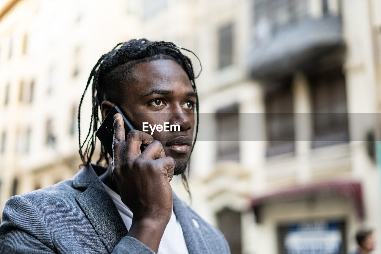 Close-up of young man talking on mobile phone in city