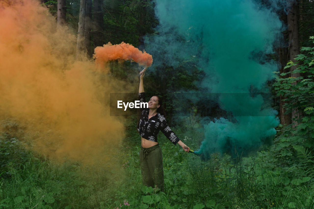 Woman standing in a forest with color smoke