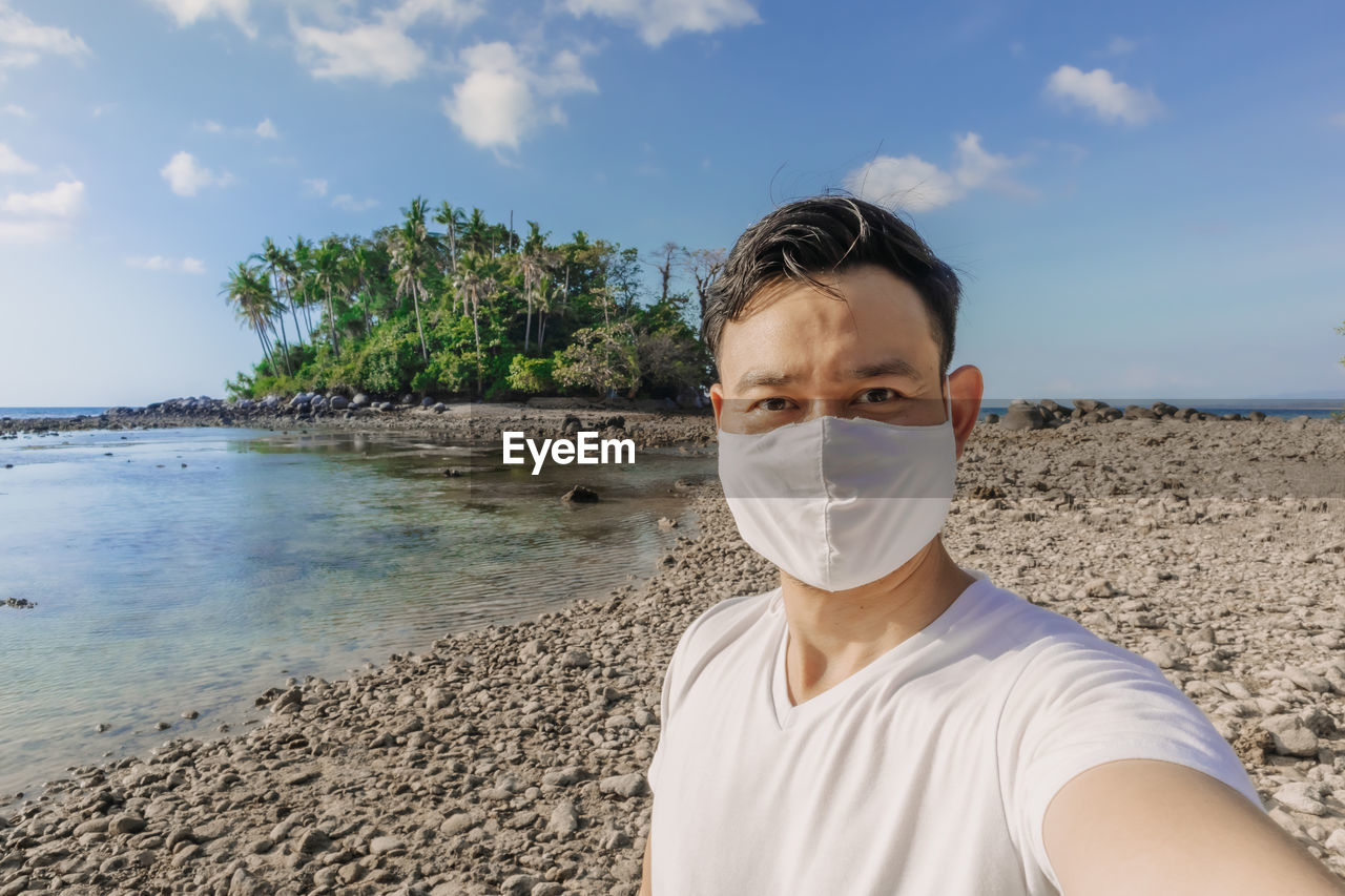 Man with face mask has a summer sea trip while in covid-19 pandemic.