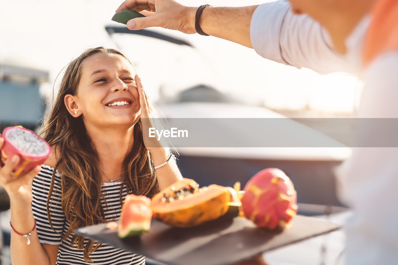 Smiling girl with father holding pitaya sitting outdoors