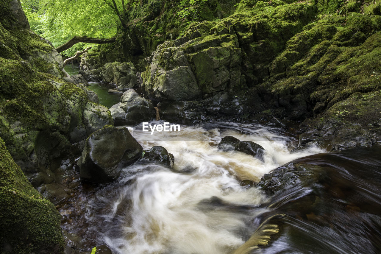 SCENIC VIEW OF WATER FLOWING THROUGH ROCKS