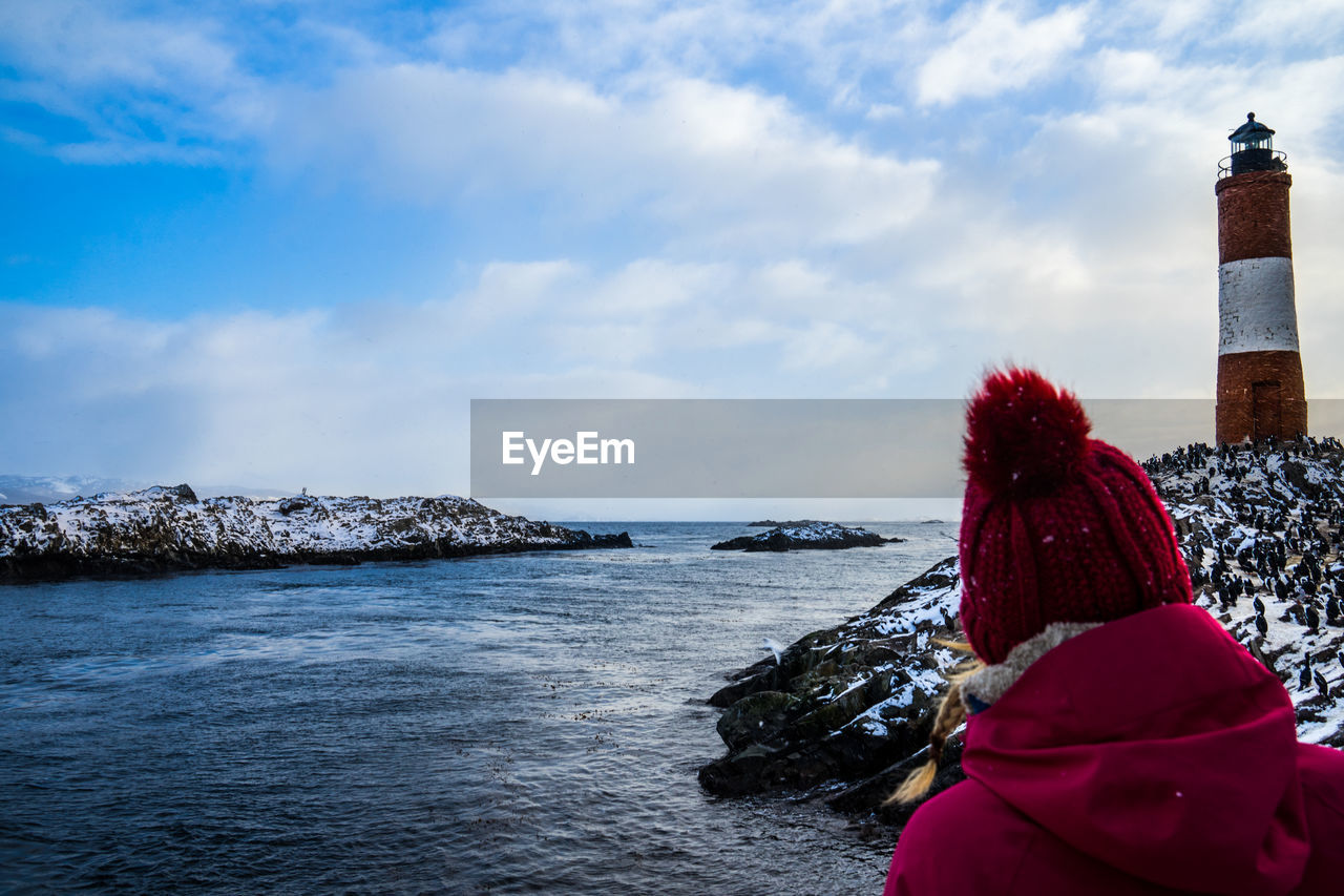 Rear view of woman looking at sea against sky during winter