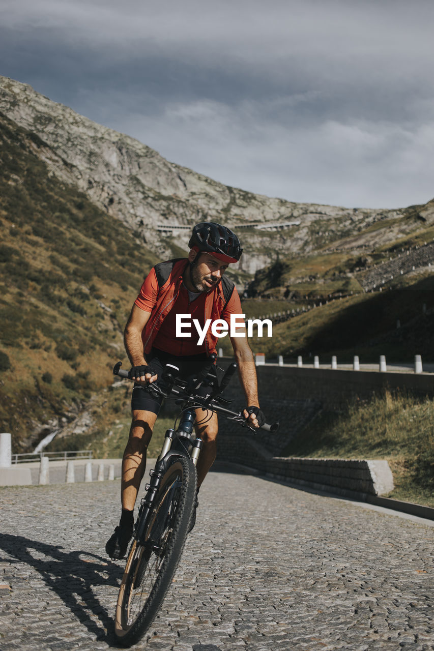 Man cycling on cobbled road at gotthard pass