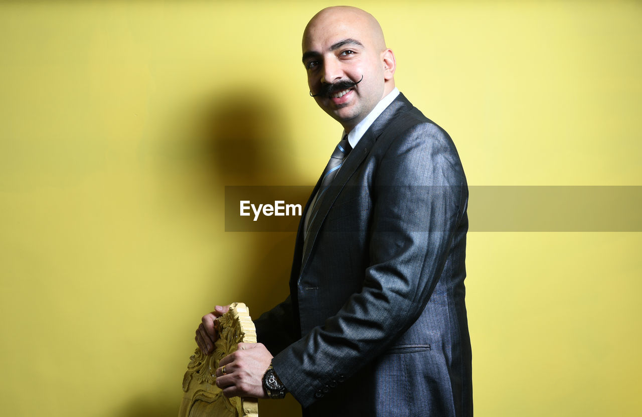 Businessman standing against yellow background